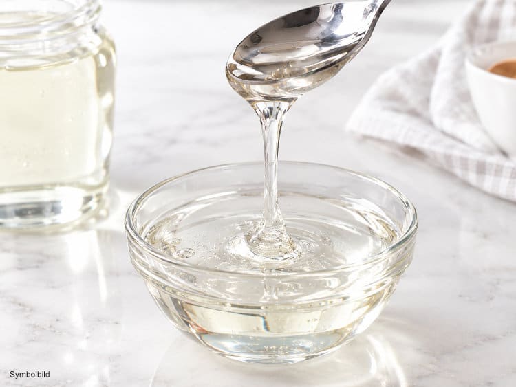 Glänzender Glukosesirup tropft von einem Löffel