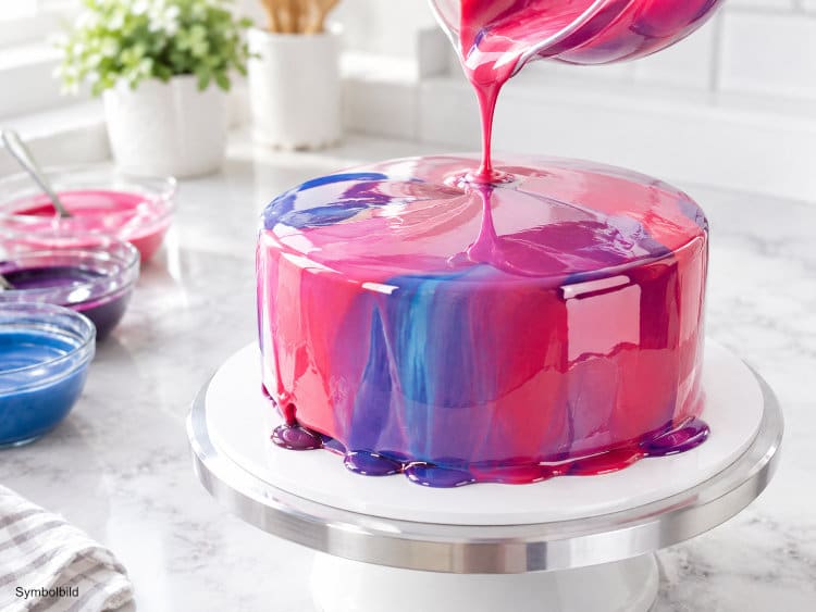 Glänzende Spiegelglasur wird über eine Torte gegossen